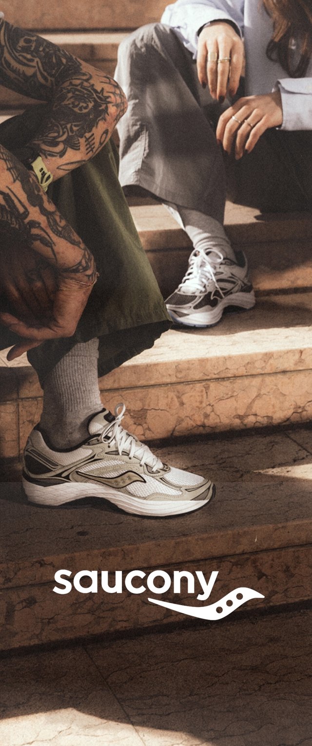 Witte Saucony sport schoenen met grijze accenten en een slank ontwerp. Een gestructureerde zool is zichtbaar. Twee personen zitten op stenen treden.