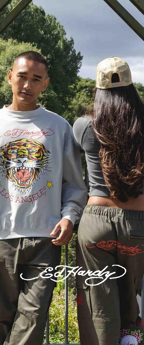 Grijze sweatshirt met een tijgerafbeelding en rode letters, gecombineerd met olijfgroene cargobroeken met geborduurd logo. Casual streetwear stijl.