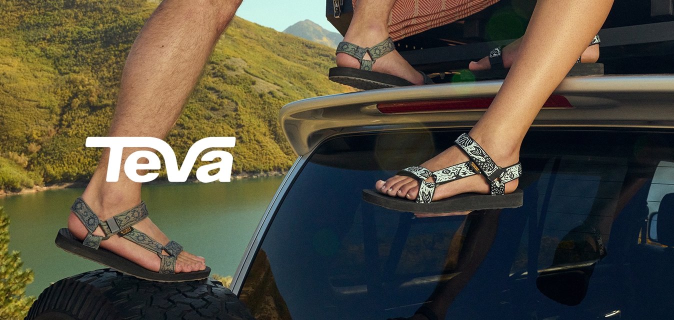 Dvě dvojice sandálů s vzorovanými popruhy, jedny šedé a jedny černé. Oba mají plochou podrážku a jsou upevněné pomocí nastavitelného přezku na střeše auta.