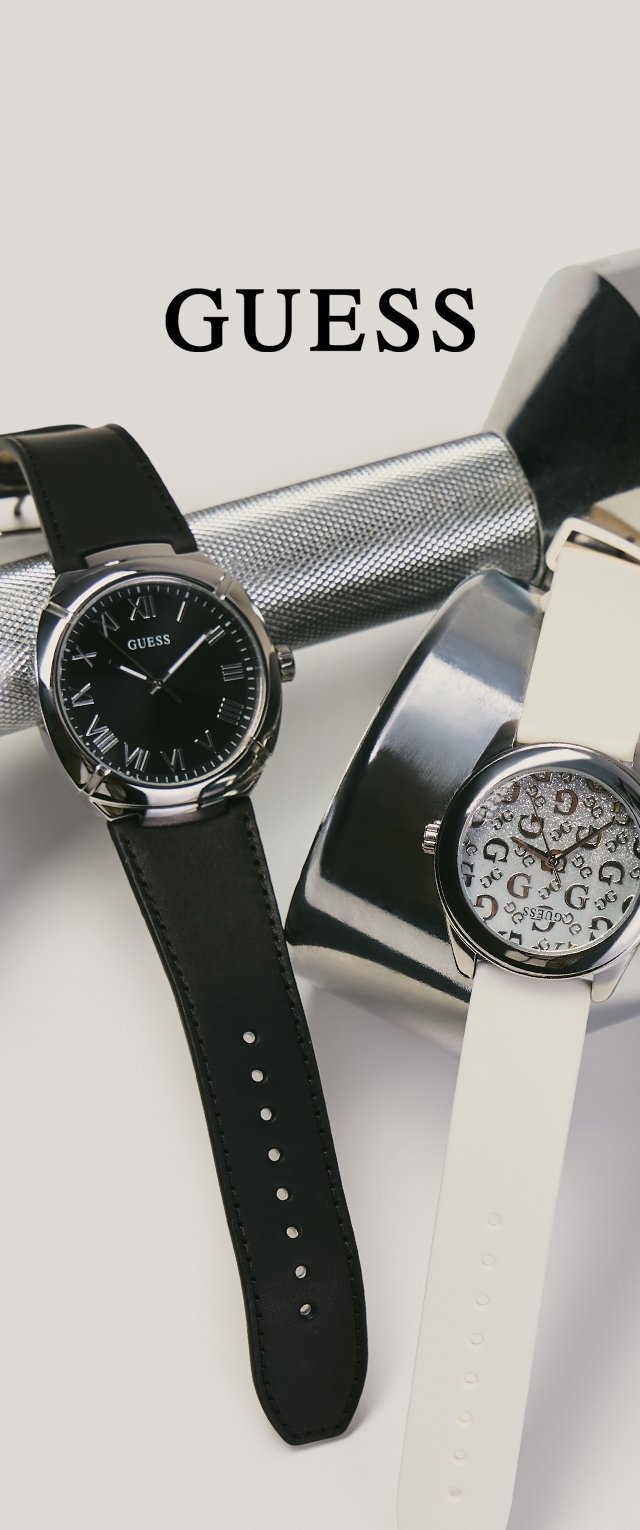 Twee Guess polshorloges met leren bandjes, één zwarte met Romeinse cijfers en één witte met een patroon op de wijzerplaat, tentoongesteld op metalen halters.