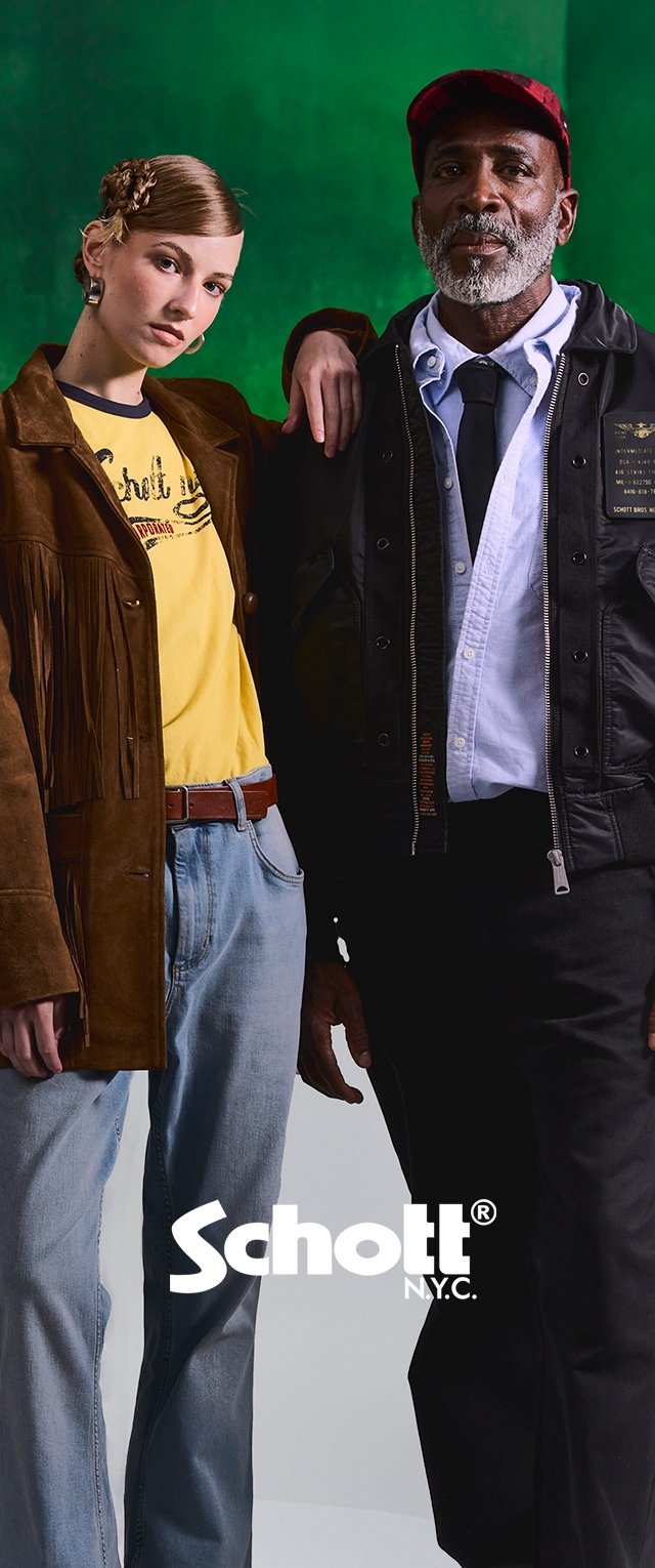 Joven mujer con chaqueta marrón con flecos y vaqueros, hombre mayor con chaqueta negra, camisa blanca y gorra roja, ambos de pie uno al lado del otro contra un fondo verde.