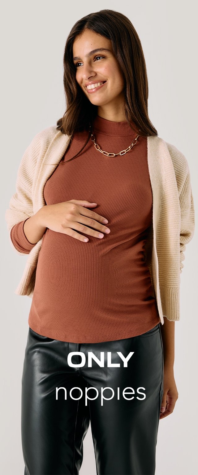 Mujer embarazada sonriente con un top de canalé marrón, cardigan beige, collar de cadena dorada y pantalones de cuero negros frente a un fondo sencillo.