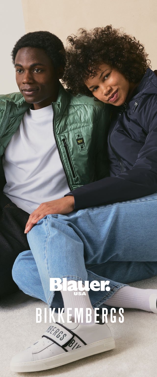Jeune homme et femme portant des vestes décontractées et des jeans, assis ensemble, avec des baskets blanches de la marque Bikkembergs visibles.